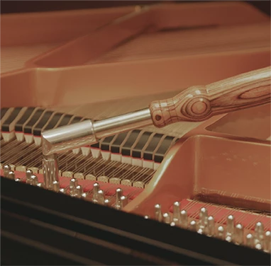Une photo d'un outil pour accorder un piano, posé sur un mécanisme de piano.